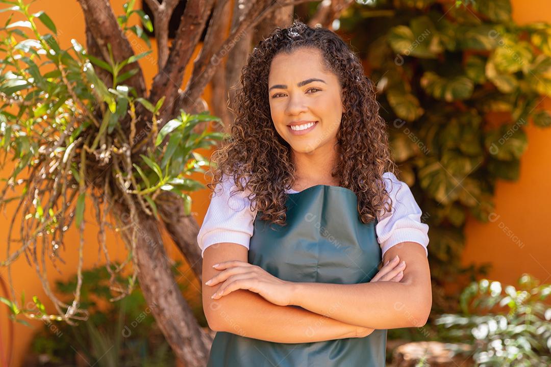 Mulher linda cabelo cacheado usando avental verde sobre fundo desfocado