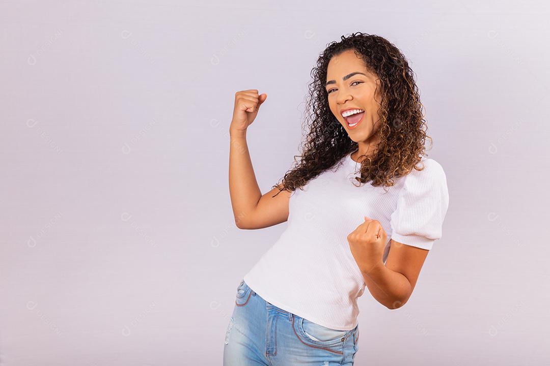 jovem afro que ganha competição grita e comemora isolado no fundo branco.