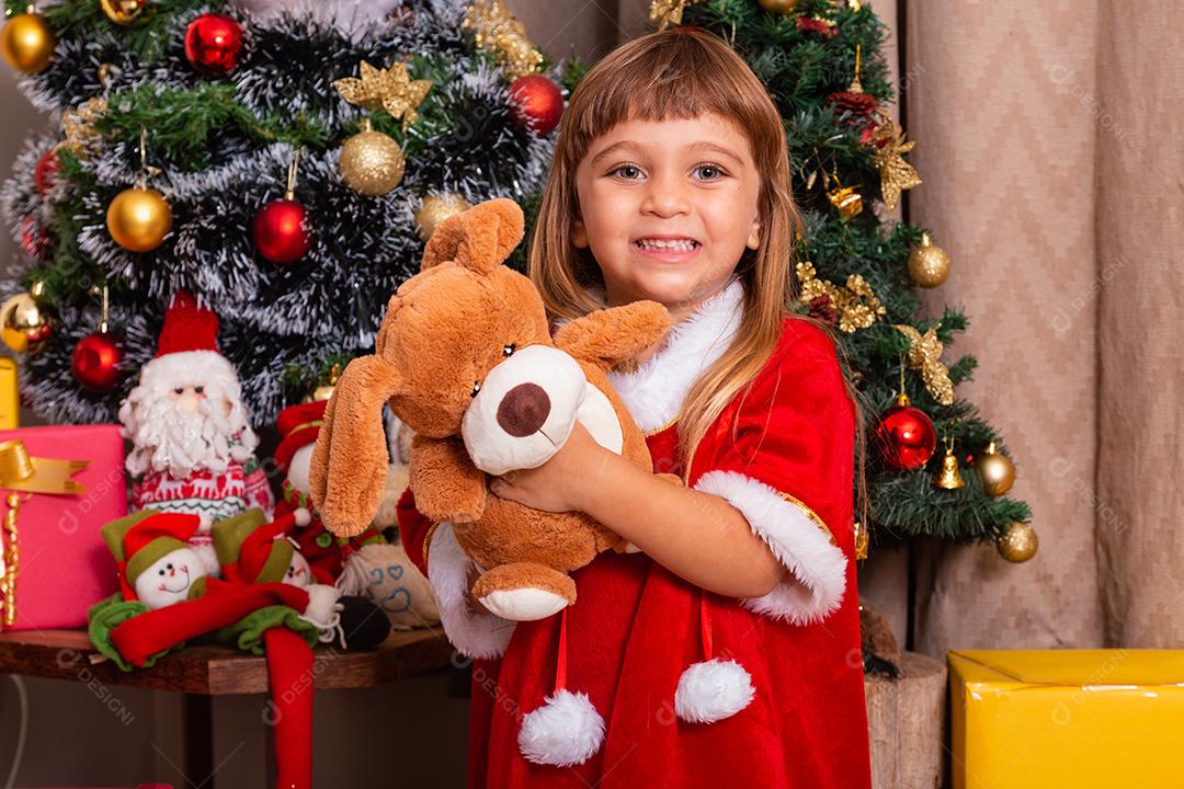 menina caucasiana bonitinha vestida para o natal em casa. Garota em fundo de Natal vestida de noelete