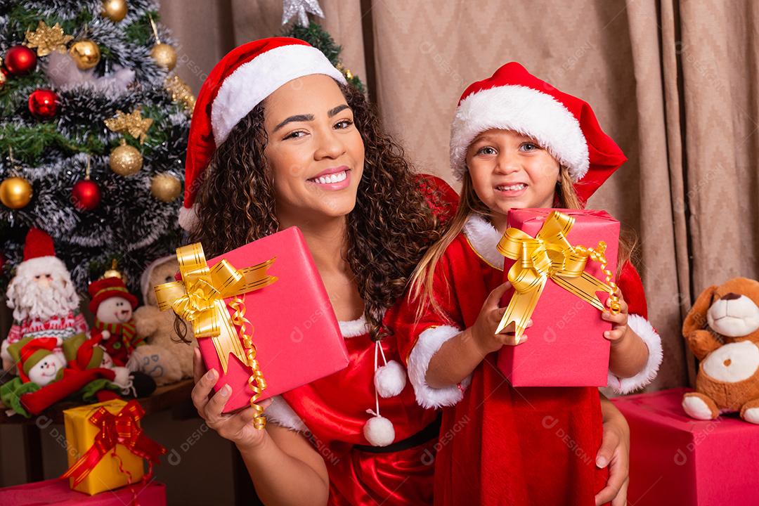 família feliz, mãe e filha com presentes de natal e chapéus na sala. Mãe e filha vestidas para a noite de Natal