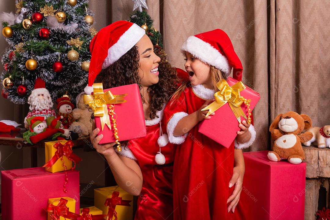 família feliz, mãe e filha com presentes de natal e chapéus na sala. Mãe e filha vestidas para a noite de Natal