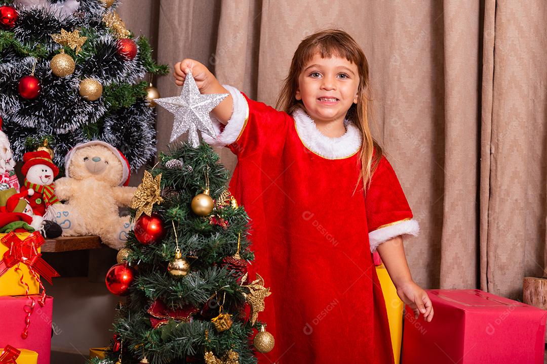 Garoto caucasiano organiza decorar a árvore de natal com o conceito de ideias festivas de natal divertidas e alegres