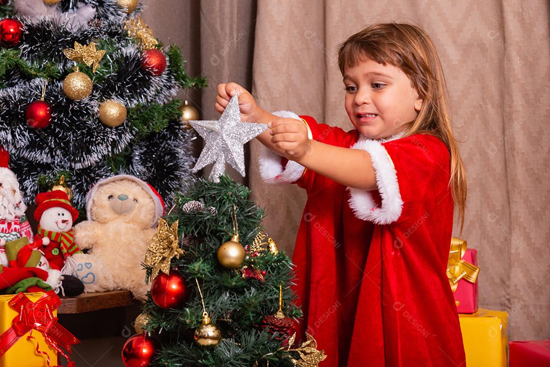 Garoto caucasiano organiza decorar a árvore de natal com o conceito de ideias festivas de natal divertidas e alegres