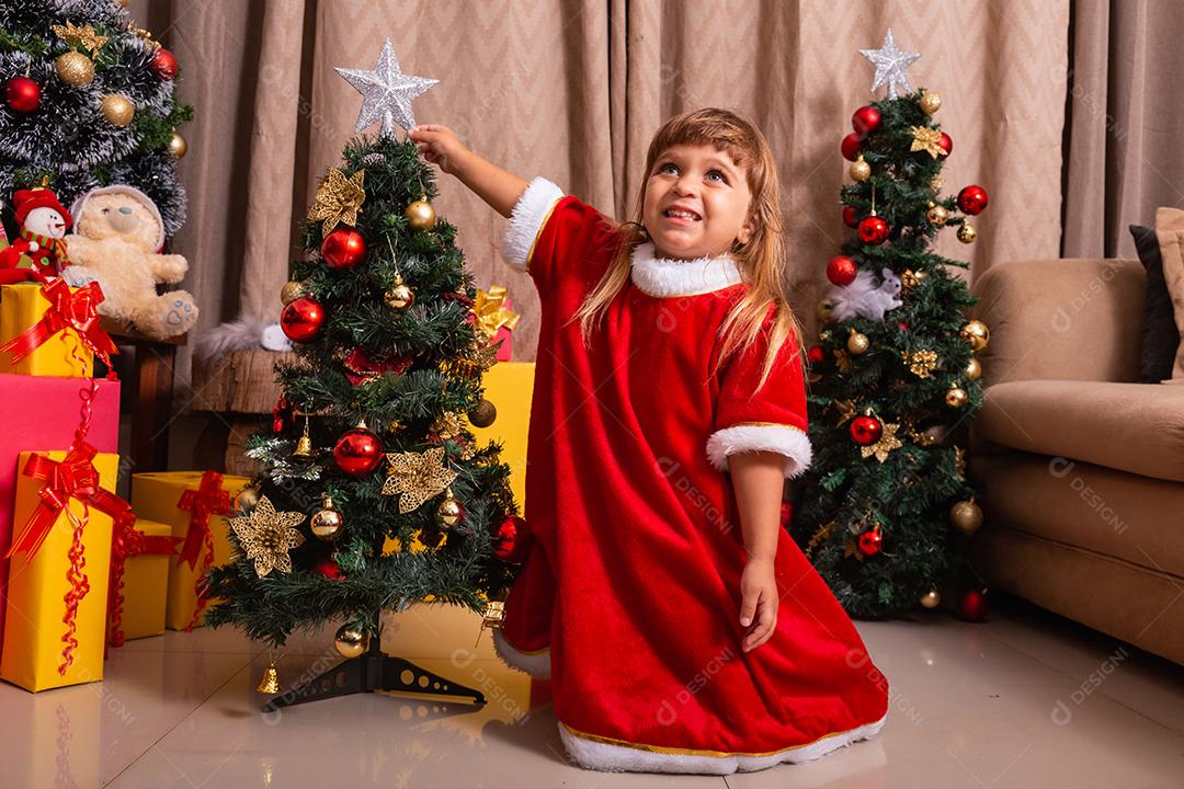 Garoto caucasiano organiza decorar a árvore de natal com o conceito de ideias festivas de natal divertidas e alegres