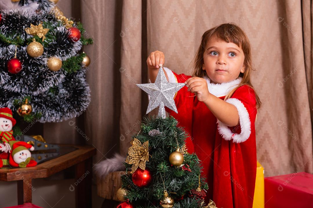 Garoto caucasiano organiza decorar a árvore de natal com o conceito de ideias festivas de natal divertidas e alegres