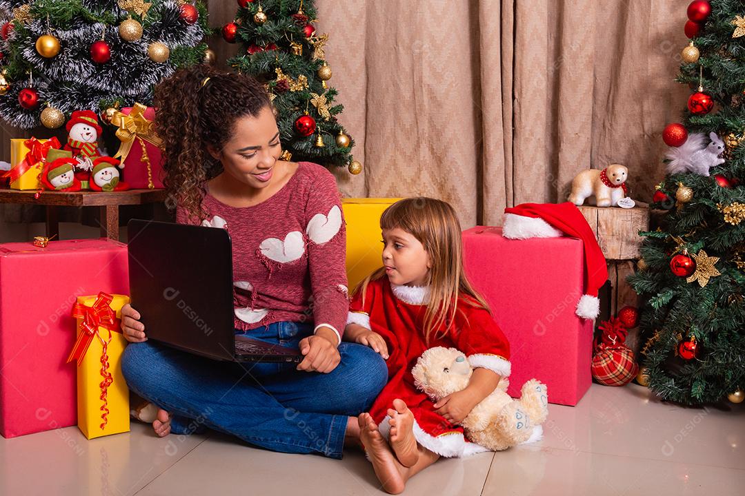 A mãe da família e a filha usam laptop em casa nas férias de Natal.