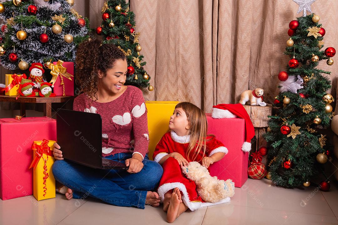 A mãe da família e a filha usam laptop em casa nas férias de Natal.