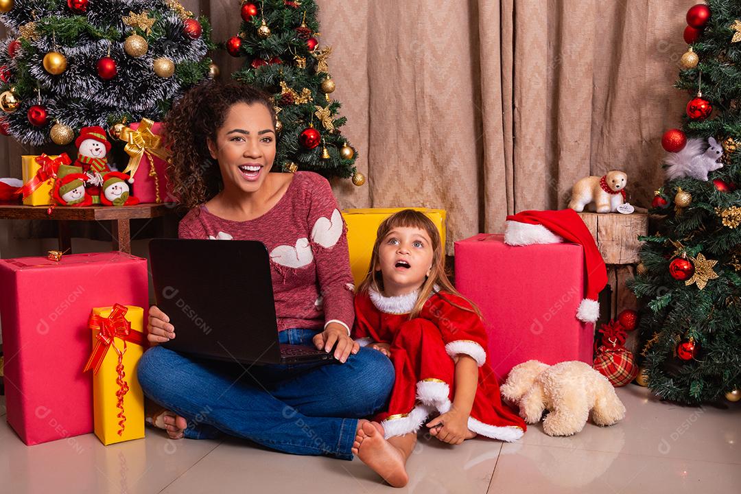 A mãe da família e a filha usam laptop em casa nas férias de Natal.