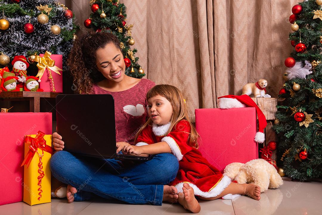 A mãe da família e a filha usam laptop em casa nas férias de Natal.
