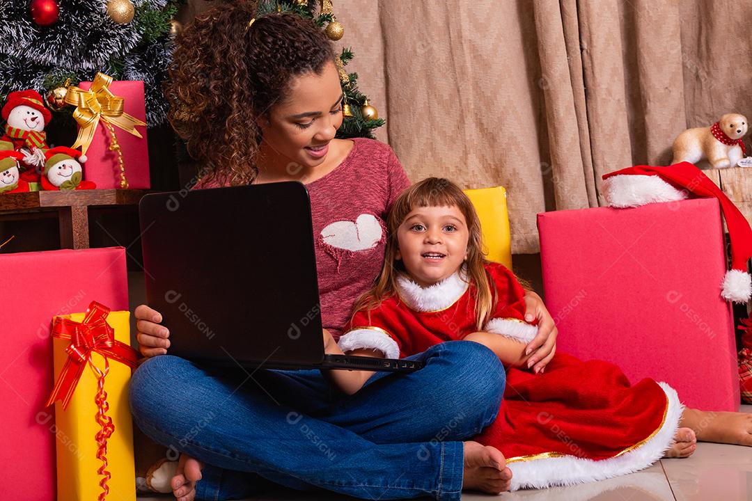 A mãe da família e a filha usam laptop em casa nas férias de Natal.