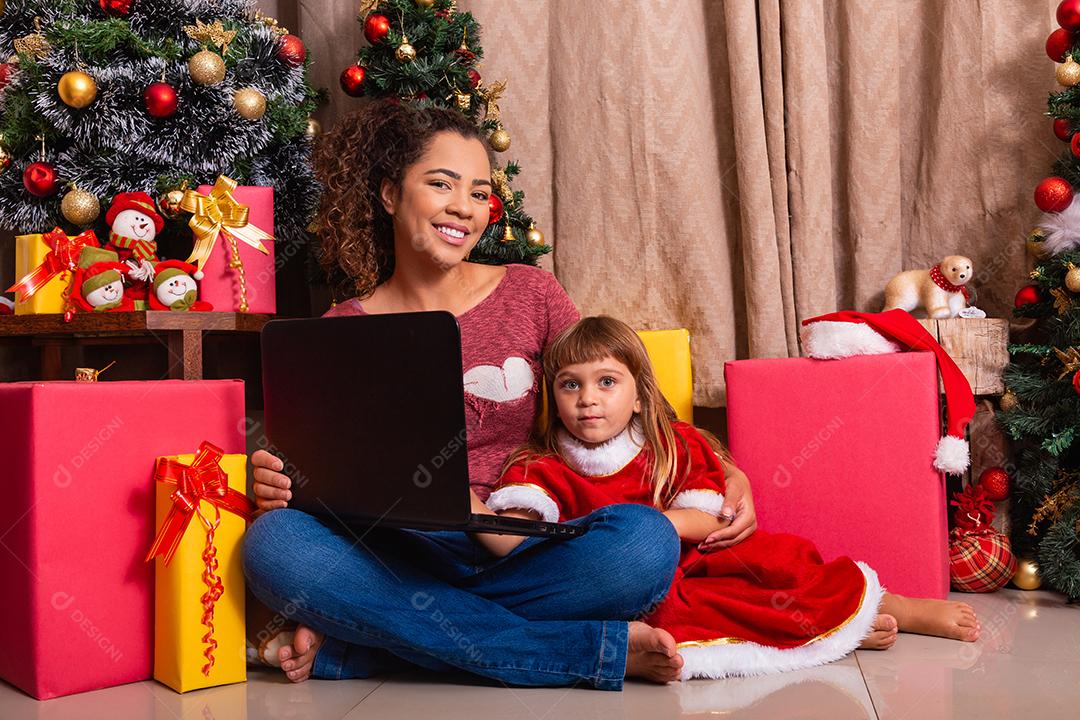 A mãe da família e a filha usam laptop em casa nas férias de Natal.