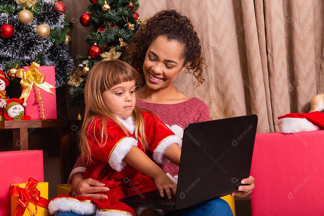 A mãe da família e a filha usam laptop em casa nas férias de Natal.