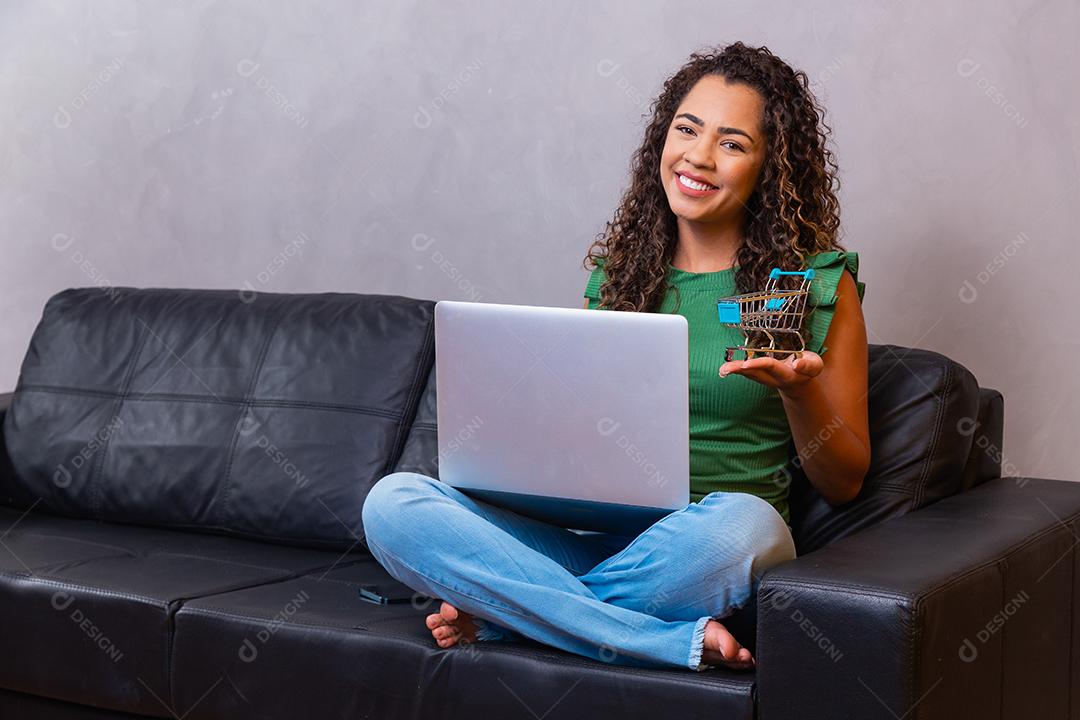 Jovem mulher sentada no sofá segurando o computador portátil pc com tela em branco vazia