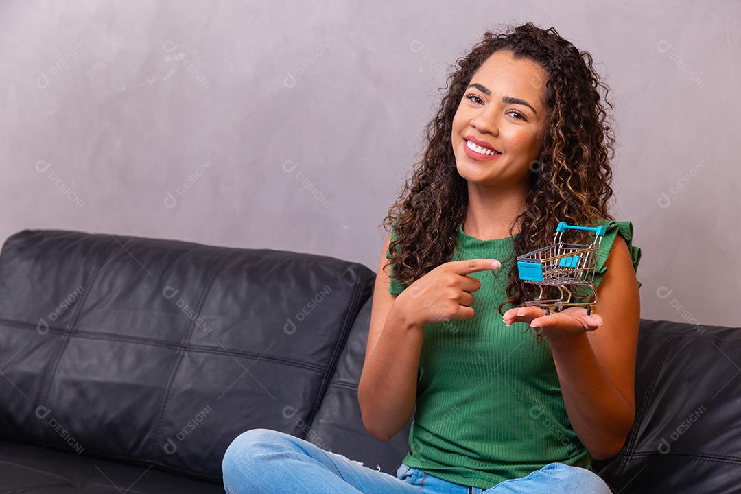 Mulher e o supermercado, ela está mostrando um mini carrinho. Conceito de compras de promoção.