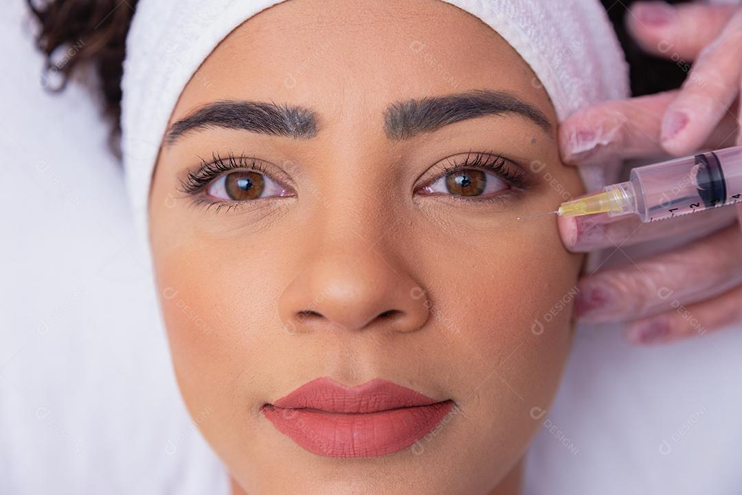 Menina bonita recebendo tratamento com ácido hialurônico. Mulher jovem e atraente está recebendo injeções faciais