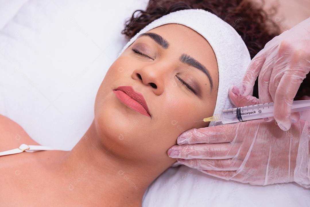 Menina bonita recebendo tratamento com ácido hialurônico. Mulher jovem e atraente está recebendo injeções faciais rejuvenescedoras.