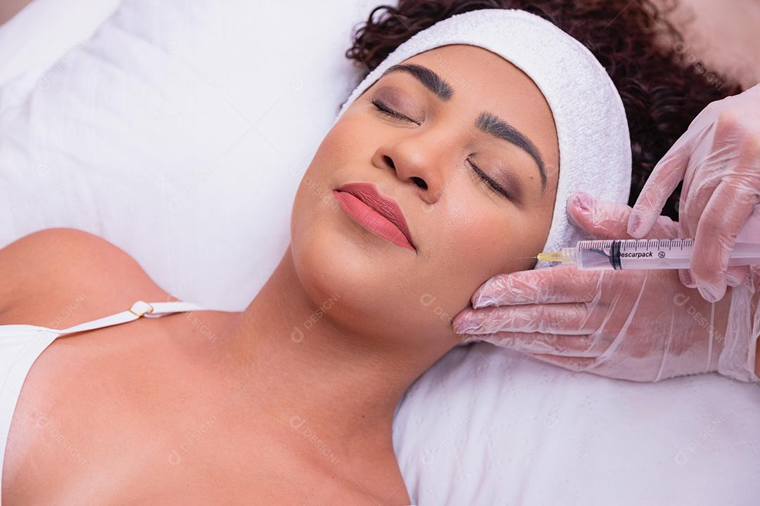 Menina bonita recebendo tratamento com ácido hialurônico. Mulher jovem e atraente está recebendo injeções faciais rejuvenescedoras.