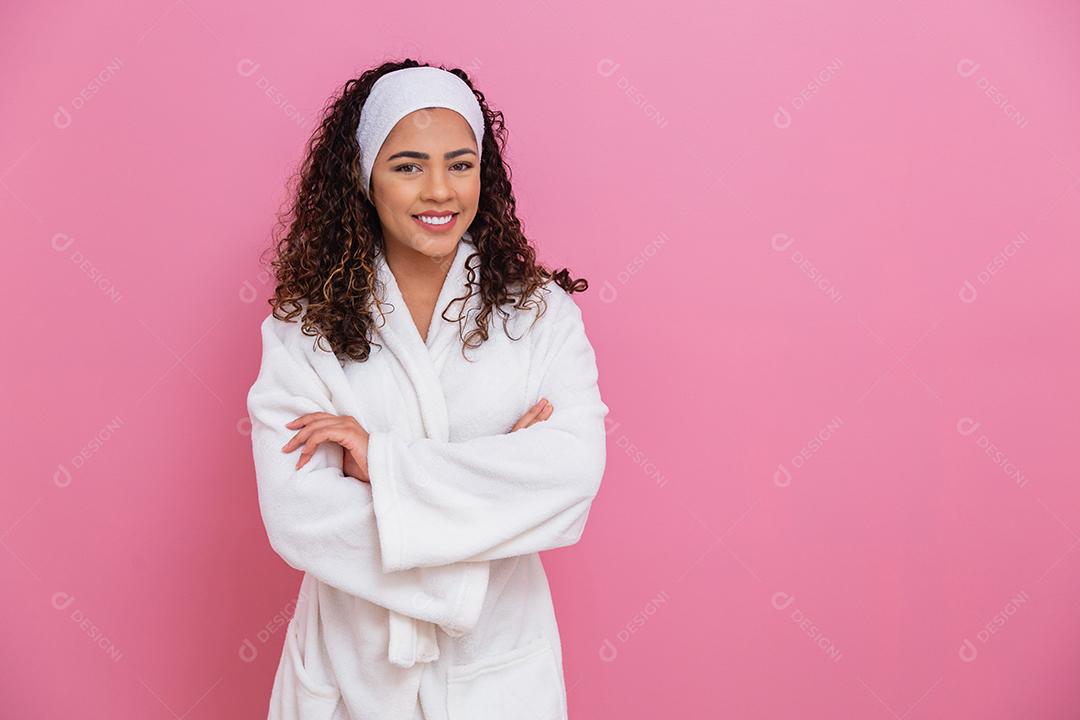 Linda garota afro vestida de roupão branco e faixa no fundo rosa conceito de saúde e cuidados