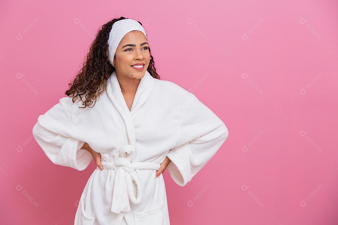 Linda garota afro vestida de roupão branco e faixa no fundo rosa conceito de saúde e cuidados