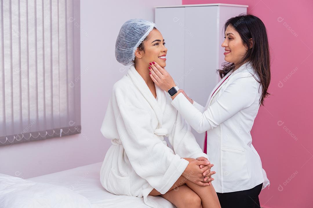 Médico ou dentista avaliando o rosto de uma linda mulher afro para tratamento estético