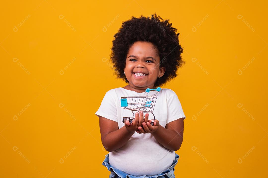 Criança no supermercado, ela está mostrando um mini carrinho. Promoção de compras