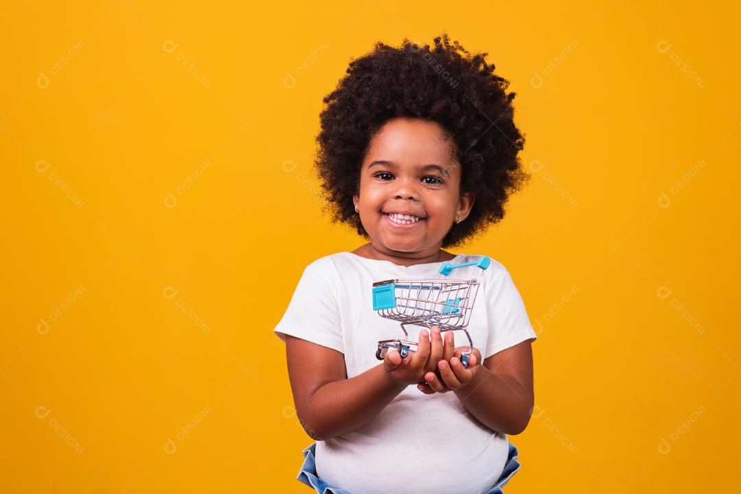 Criança no supermercado, ela está mostrando um mini carrinho. Promoção de compras