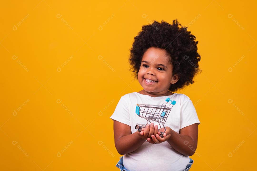 Criança no supermercado, ela está mostrando um mini carrinho. Promoção de compras