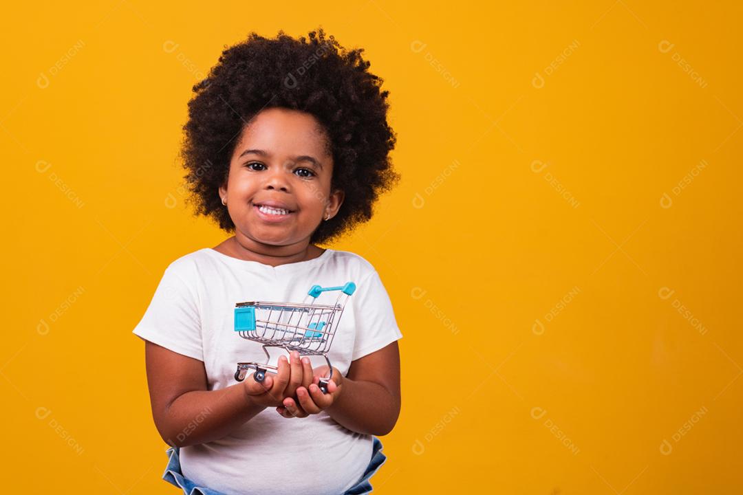 Criança no supermercado, ela está mostrando um mini carrinho. Promoção de compras