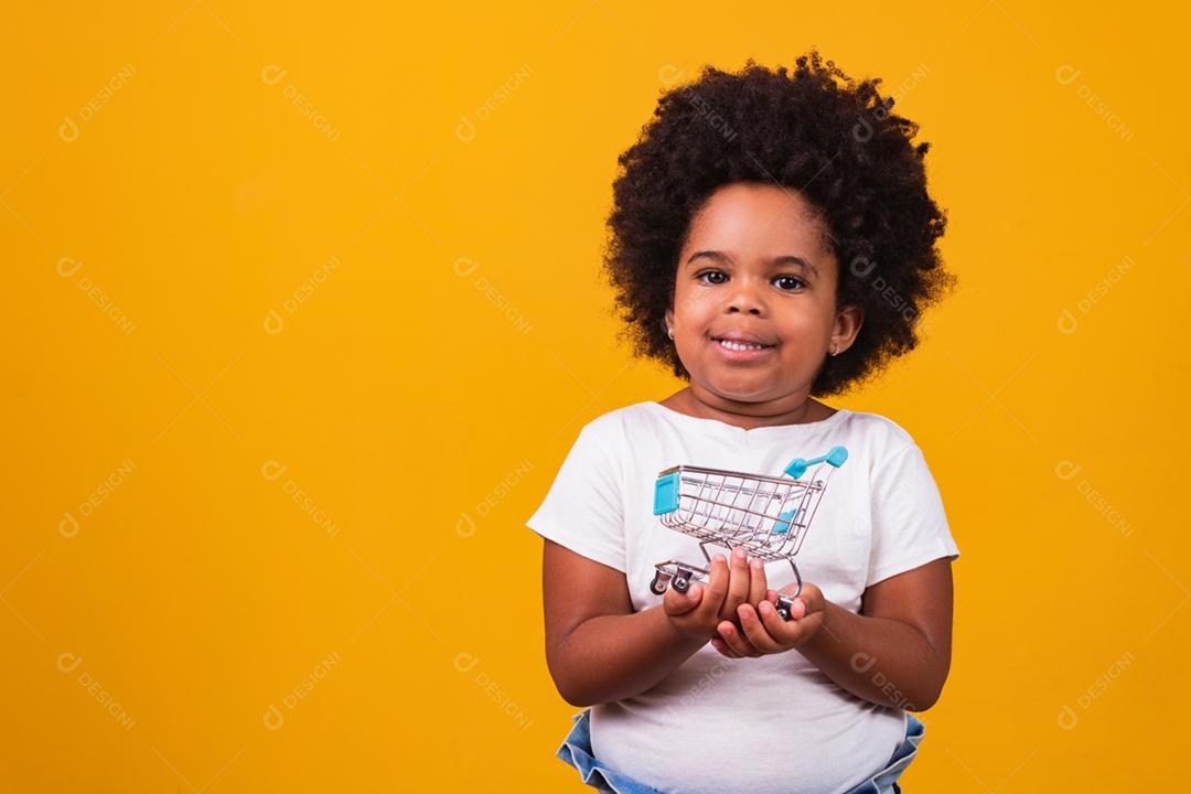 Criança no supermercado, ela está mostrando um mini carrinho. Promoção de compras