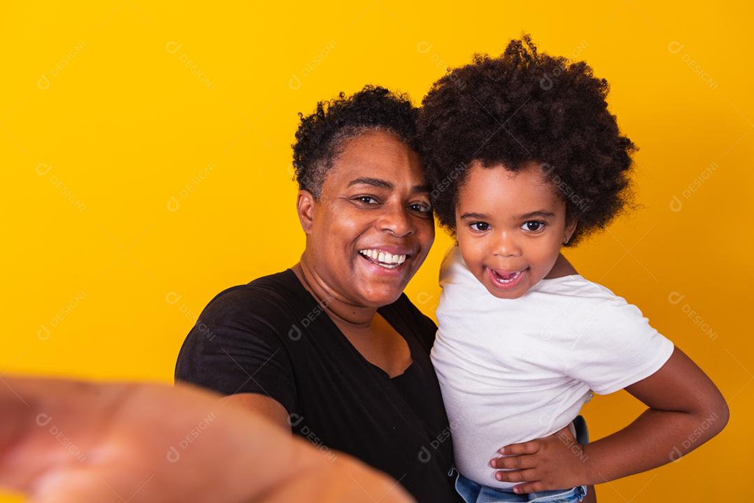 mãe mais velha com sua filha fazendo uma selfie no backgro amarelo