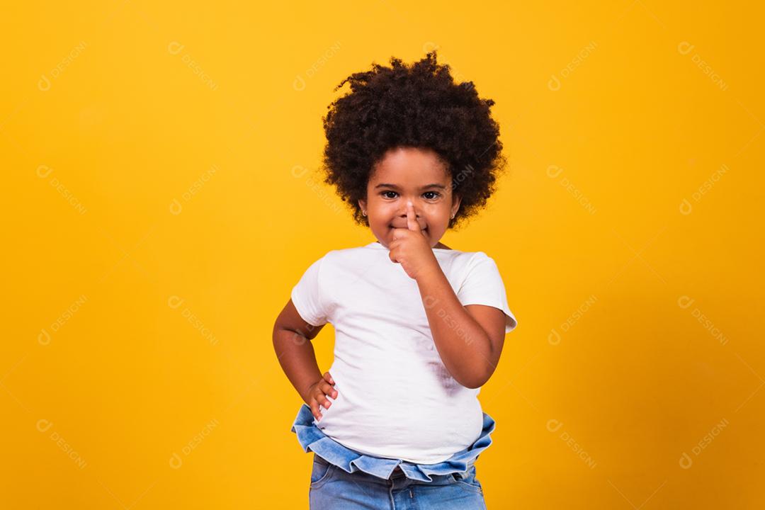 Menina  com o dedinho no nariz  em fundo amarelo