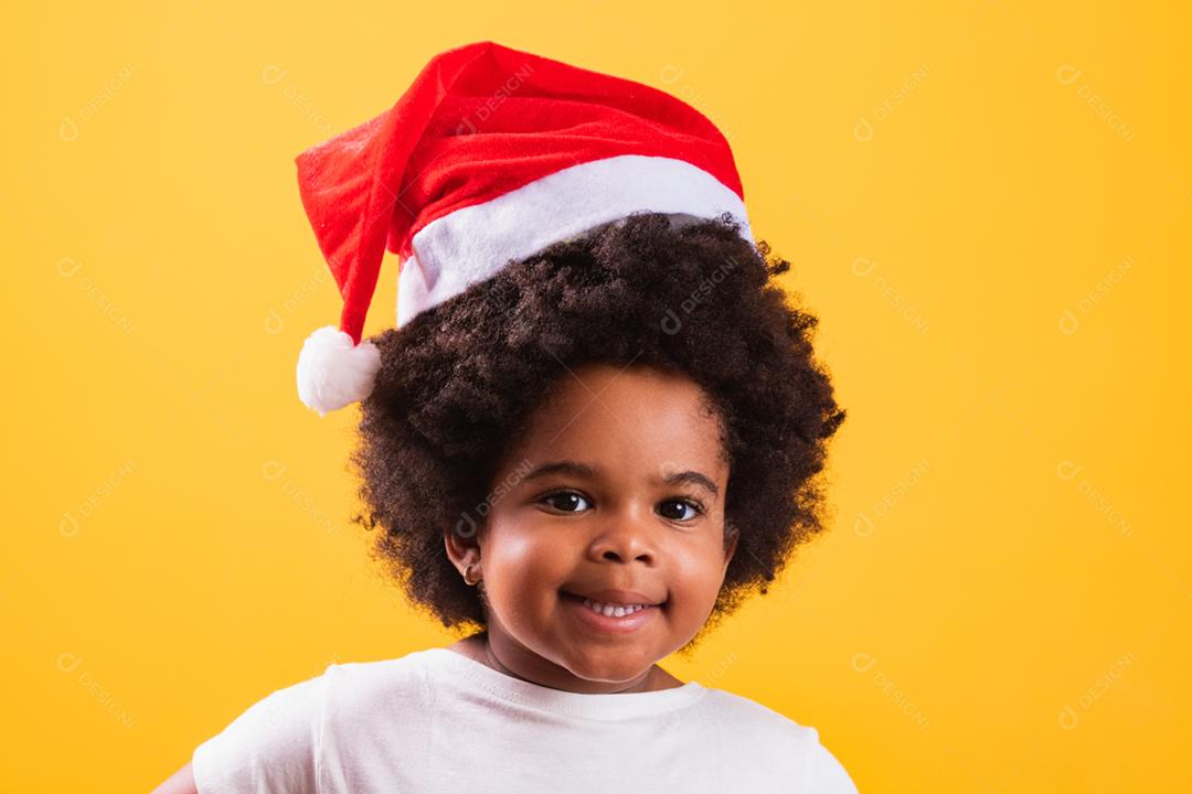 Menina afro com chapéu de Papai Noel sorrindo para o camer