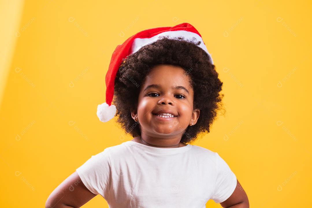 Menina afro com chapéu de Papai Noel sorrindo para o camer