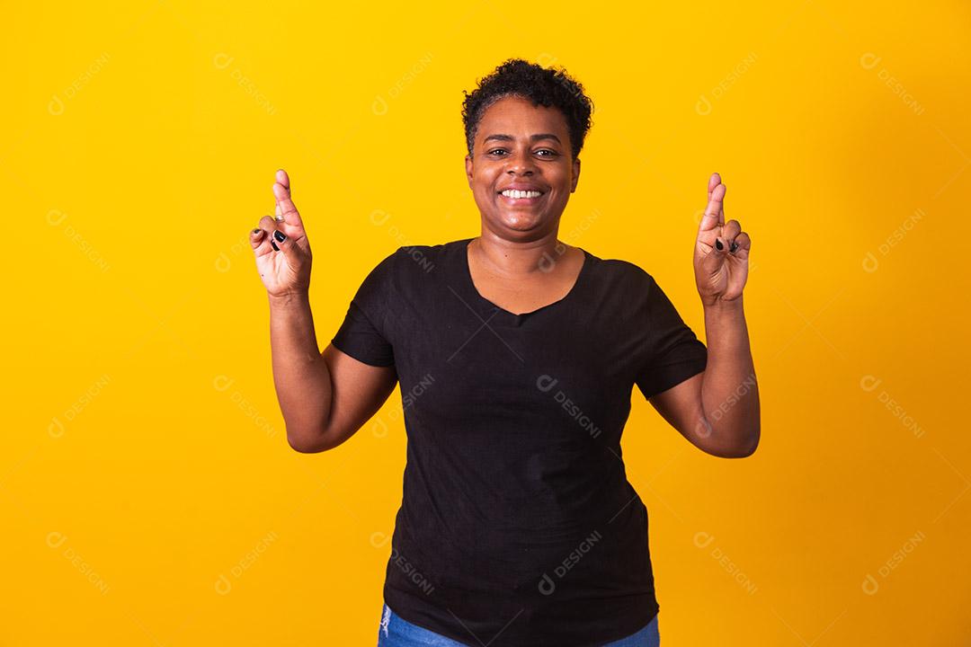 mulher negra com dedos cruzados desejando sorte