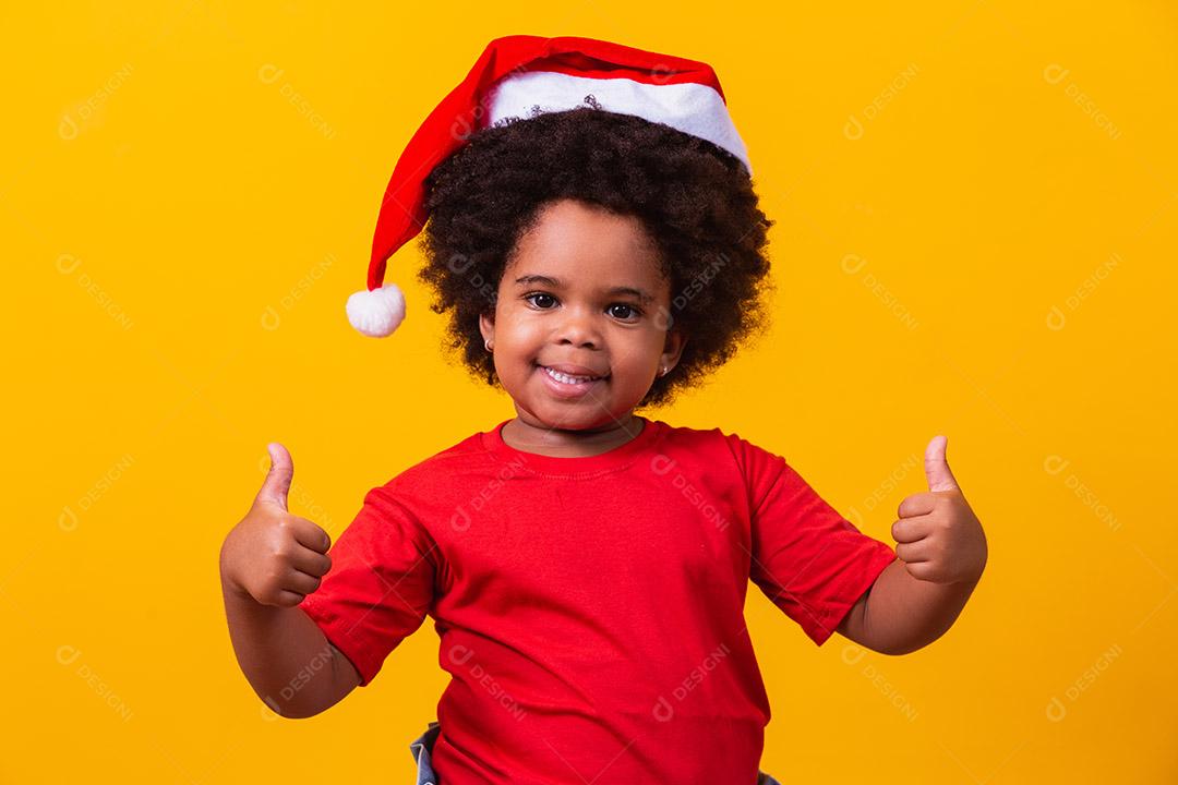 Menina afro com chapéu de Papai Noel.