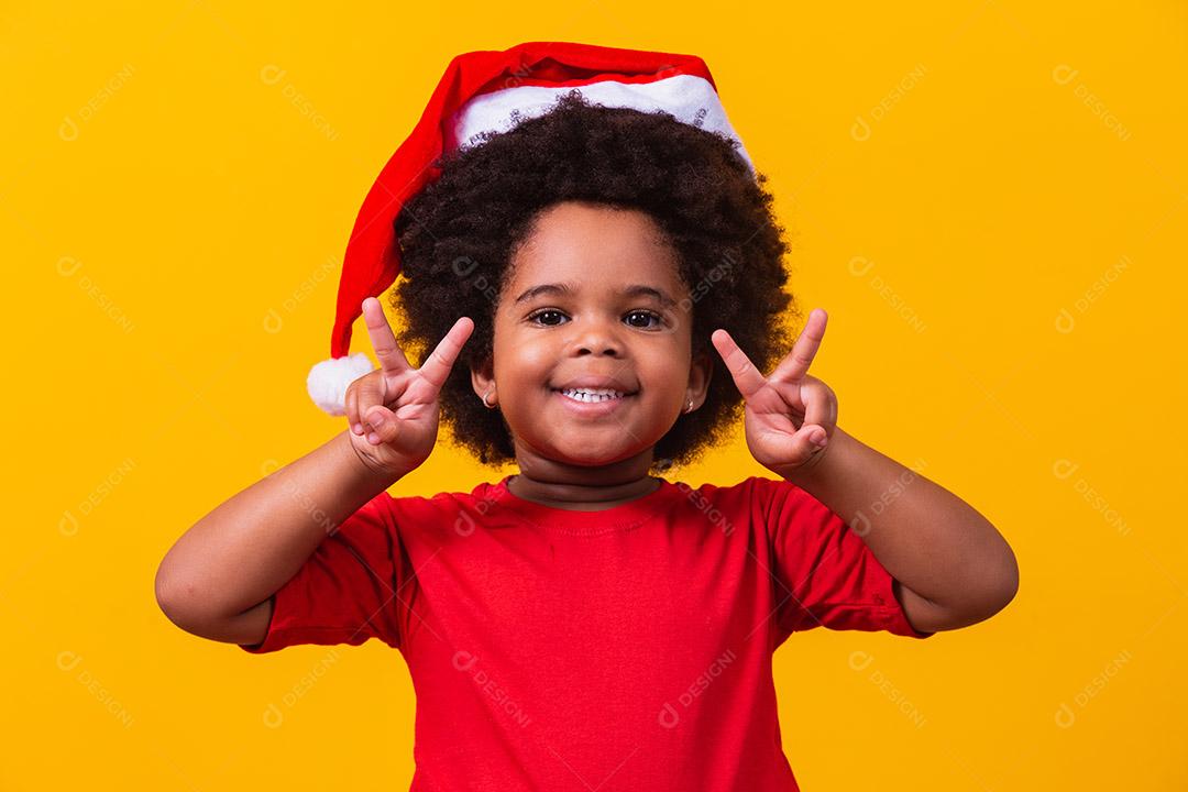 Menina afro com chapéu de Papai Noel.