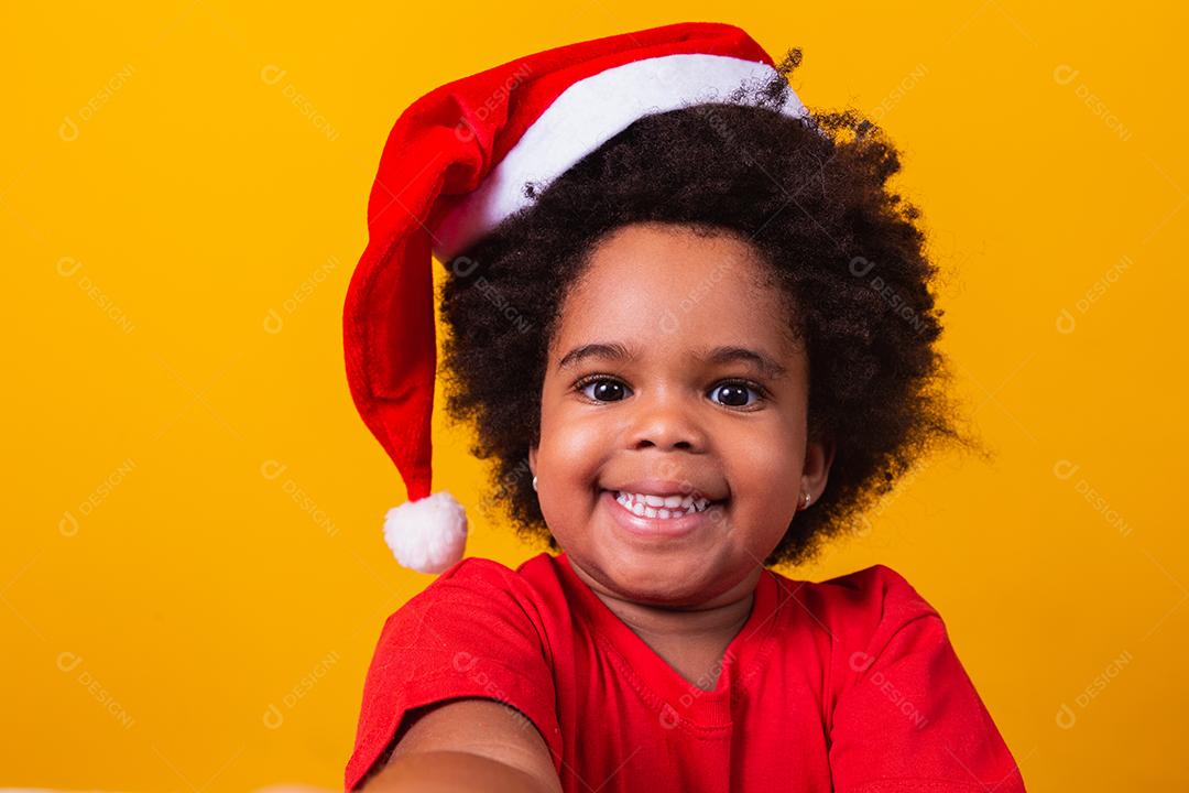 Menina afro com chapéu de Papai Noel.