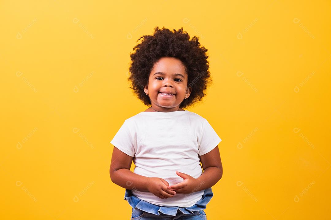 conceito de infância e pessoas - feliz garotinha afro-americana em fundo amarelo. Menina negra com cabelo preto sorrindo.