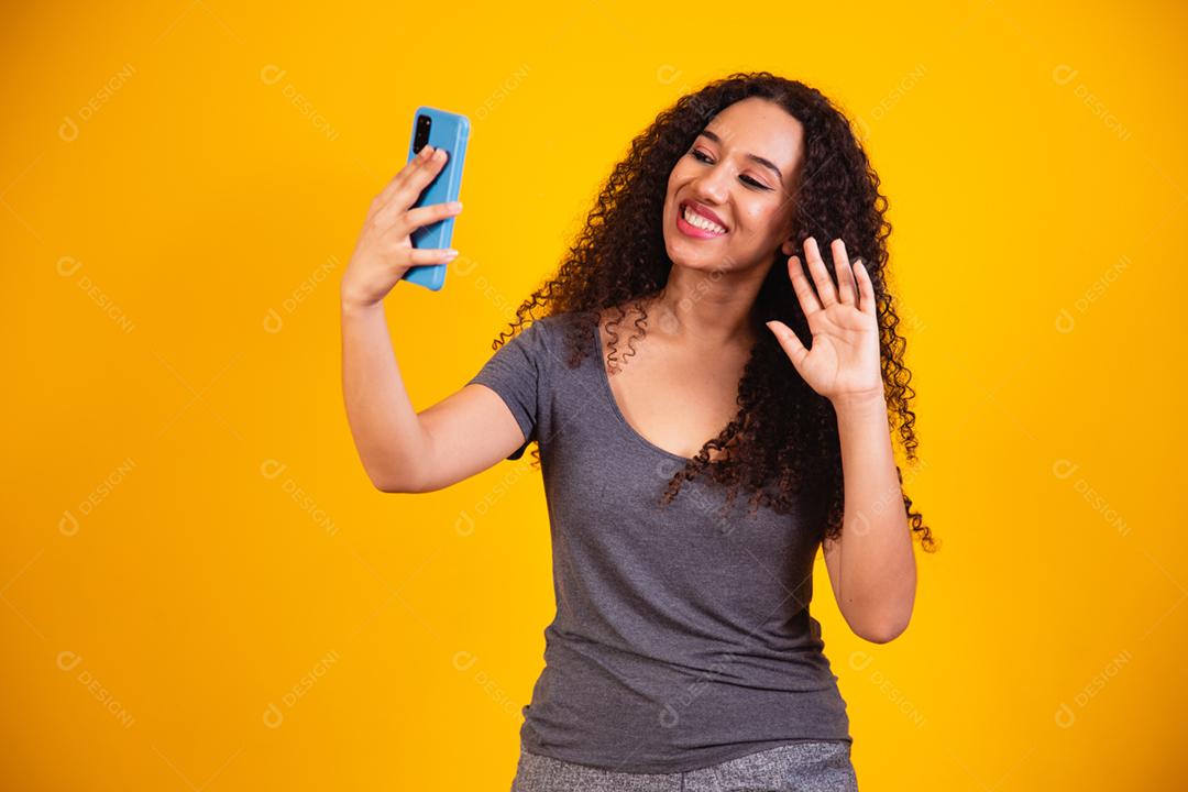 retrato de jovem afro em videochamada por telefone celular em amarelo
