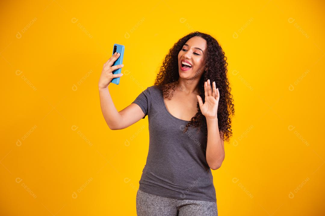 retrato de jovem afro em videochamada por telefone celular em amarelo