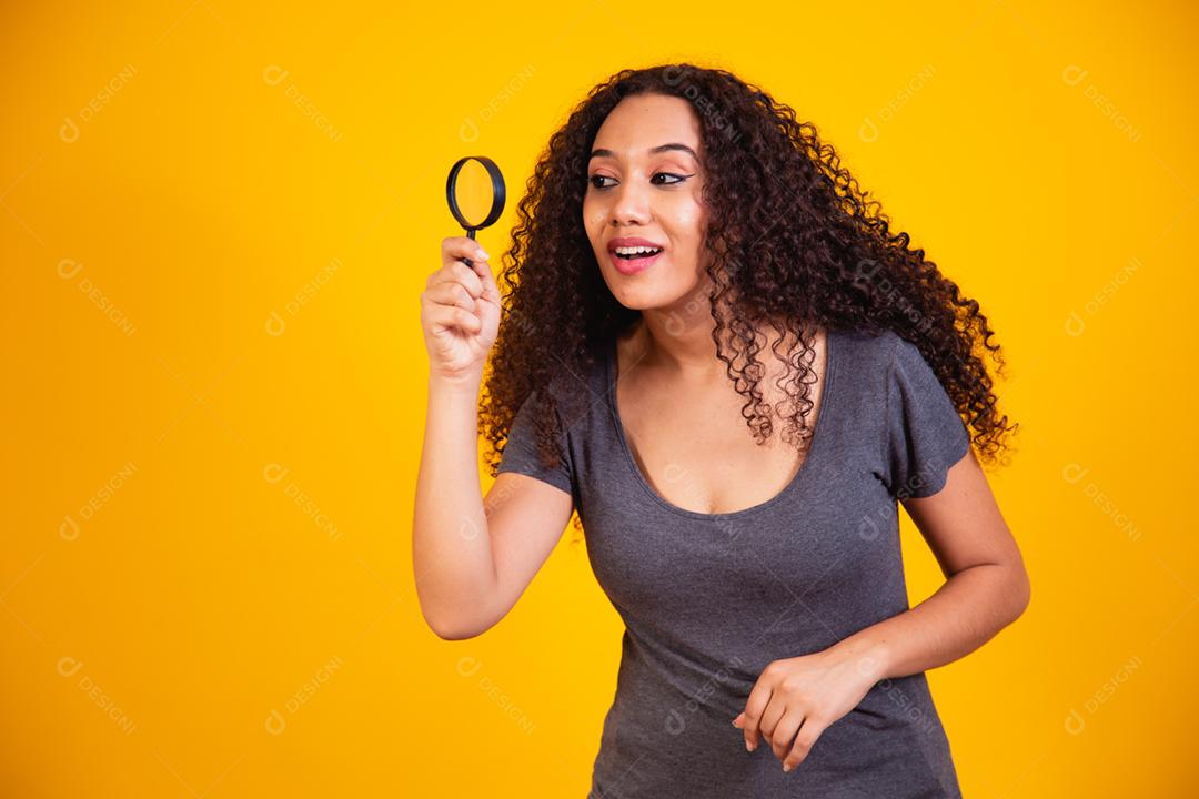 Foto de uma jovem mulher de pele escura feliz segurando o vidro da lupa de mãos