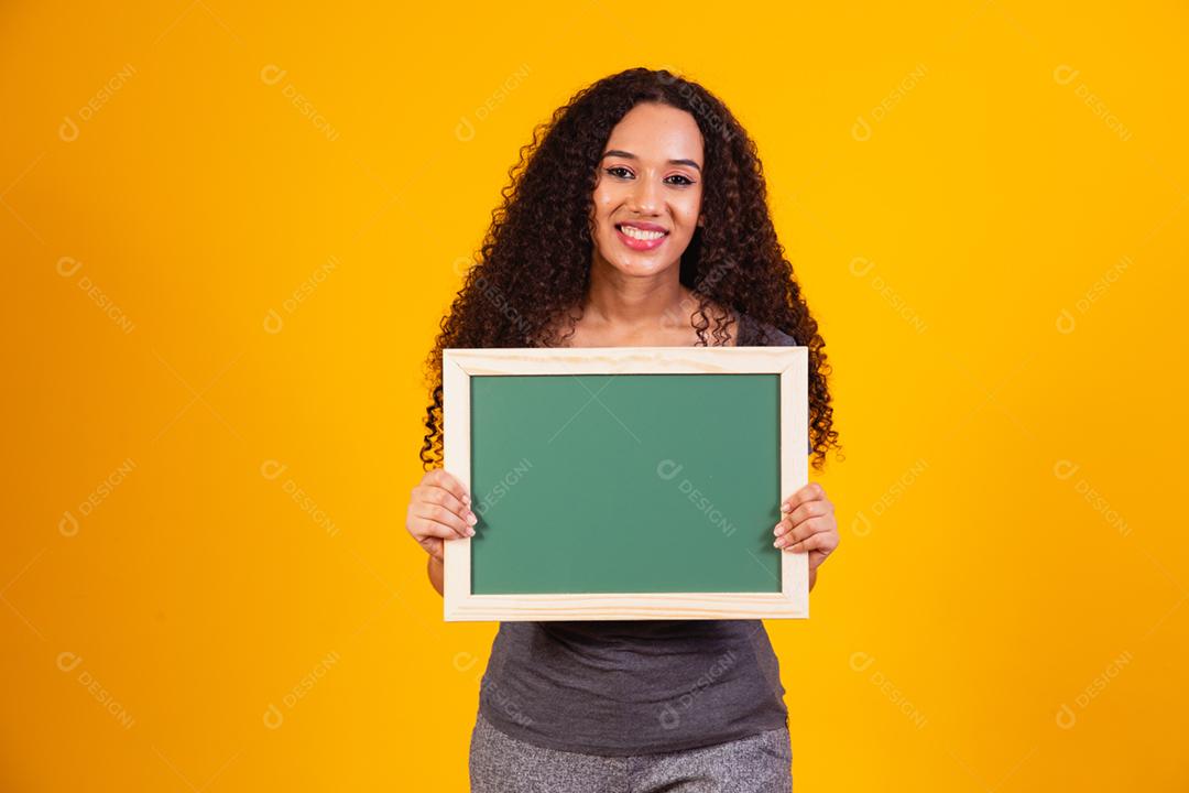 Bela jovem afro segurando um quadro-negro com espaço livre