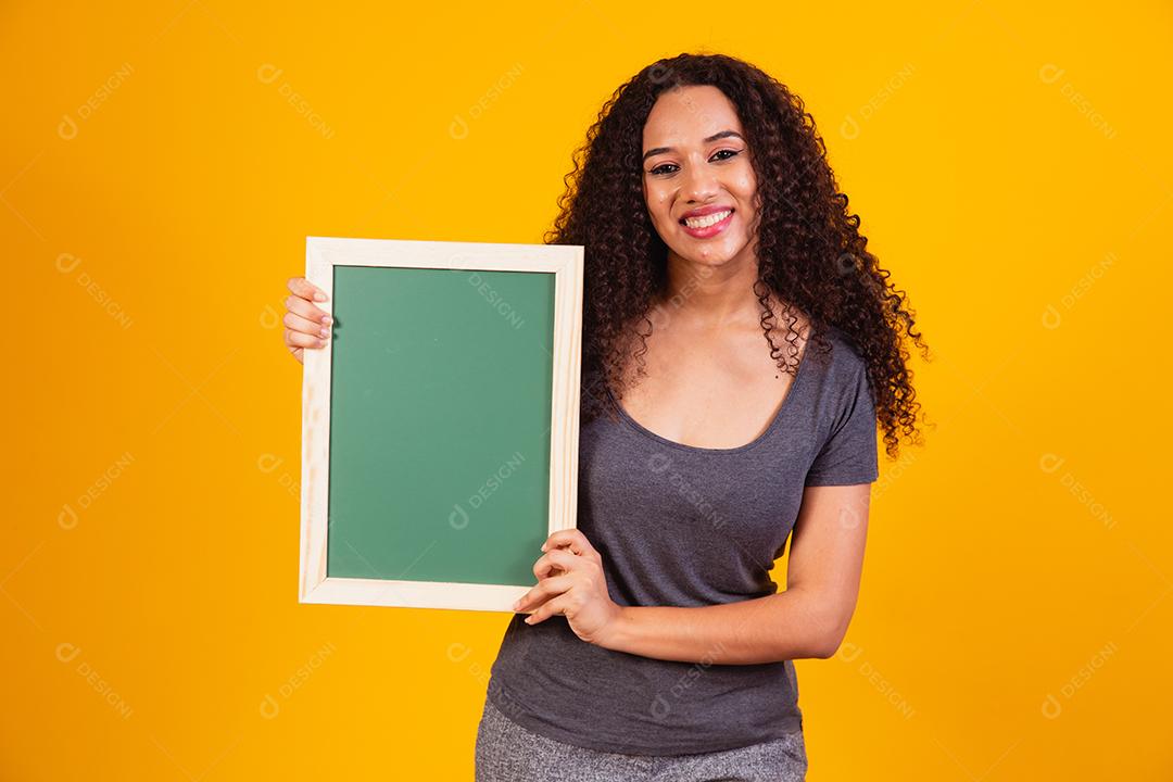 Bela jovem afro segurando um quadro-negro com espaço livre