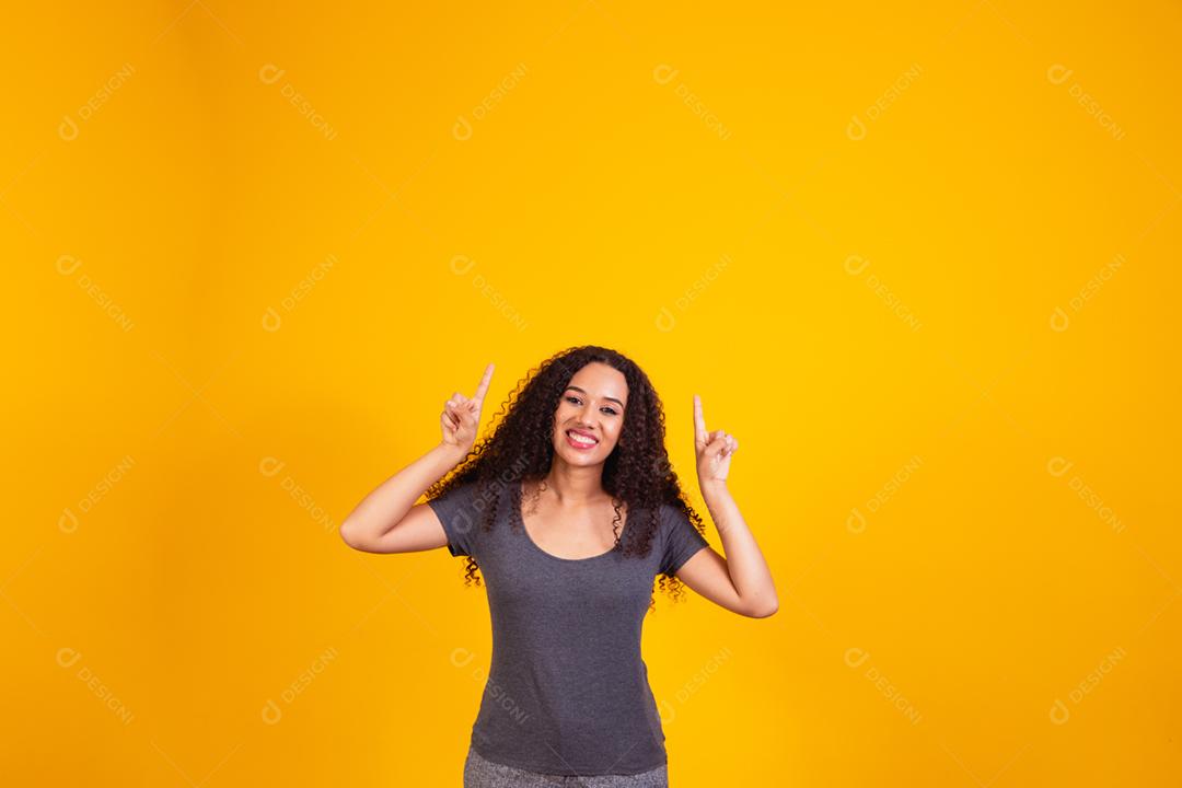 mulher afro apontando para cima com espaço livre para texto.