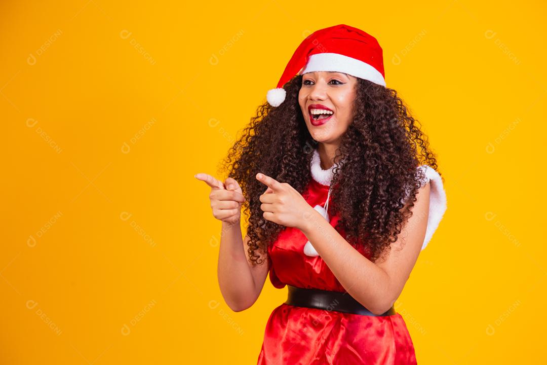 jovem noelete vestida para o natal apontando para o espaço livre
