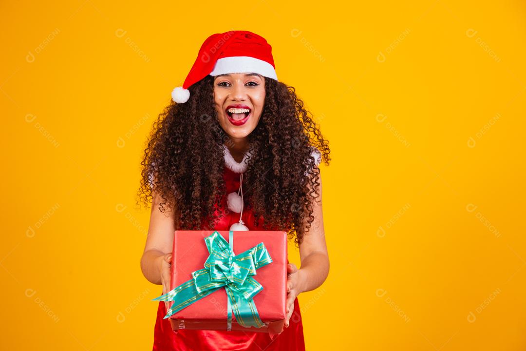 jovem noelete vestida para o natal segurando um presente em amarelo