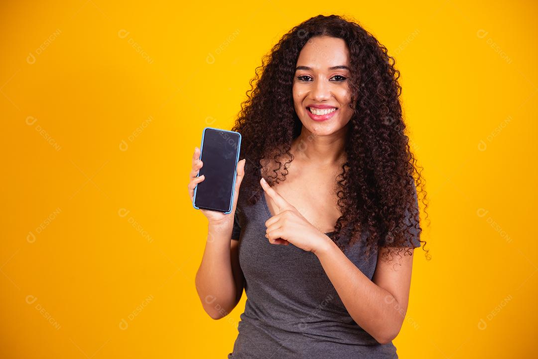 Garota afro-americana espantada apontando para a tela do telefone em branco