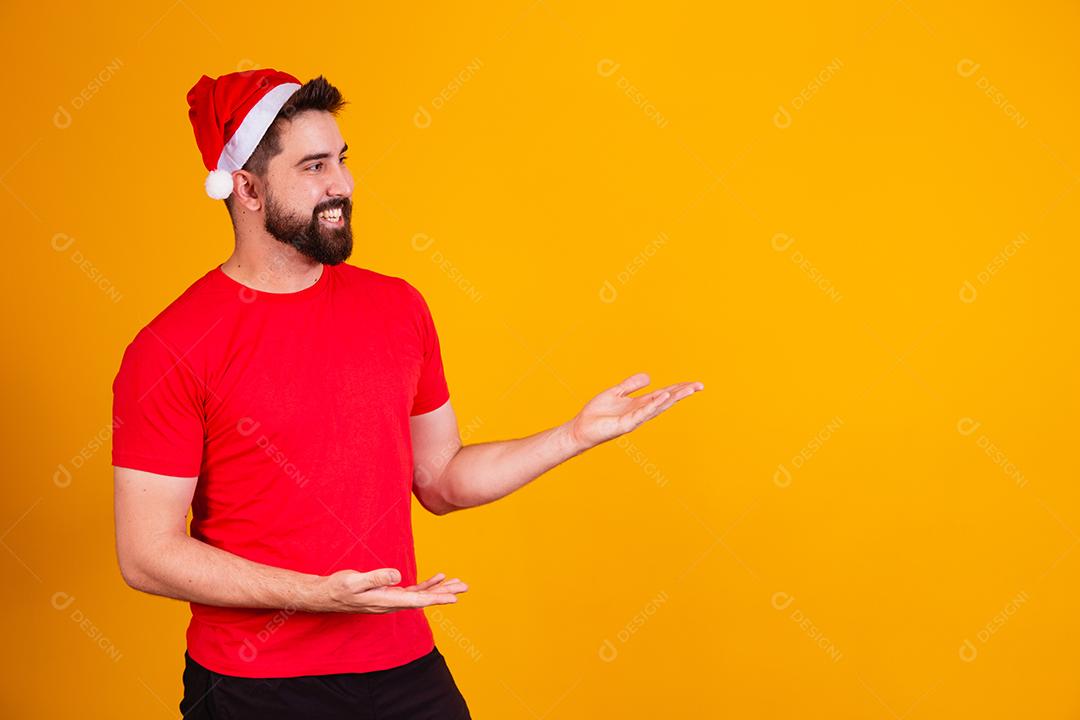 homem bonito vestido para o natal com chapéu de papai noel apontando promoção de fim de ano