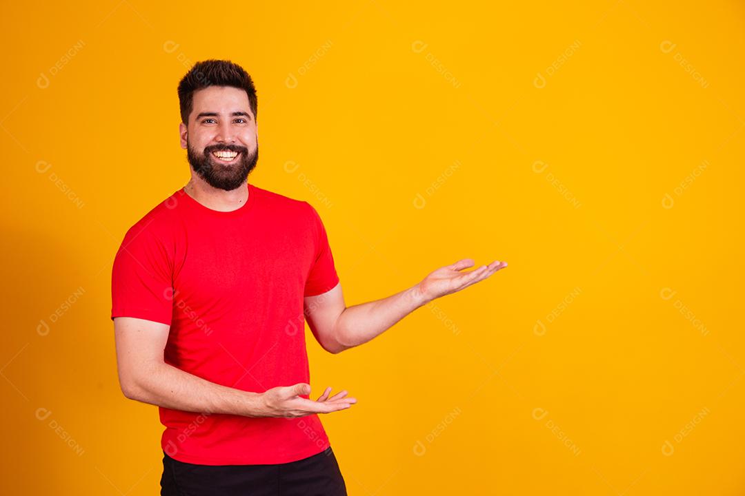 Homem bonito com barba apontando para o lado sorrindo olhando para a câmera.