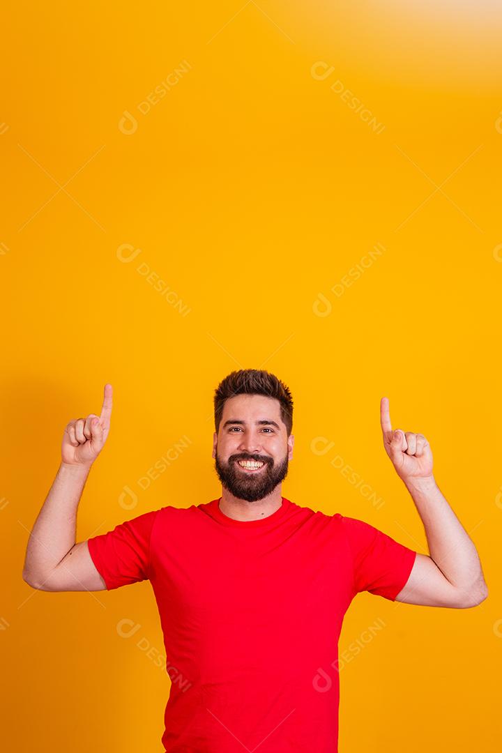 homem com barba apontando para cima no espaço livre para texto em fundo amarelo.